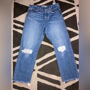 Blue light wash Levi’s straight jeans, button up, distressed hem at bottom.